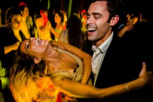 Energetic dance scene at a party with warm yellow lighting creating a joyful atmosphere.