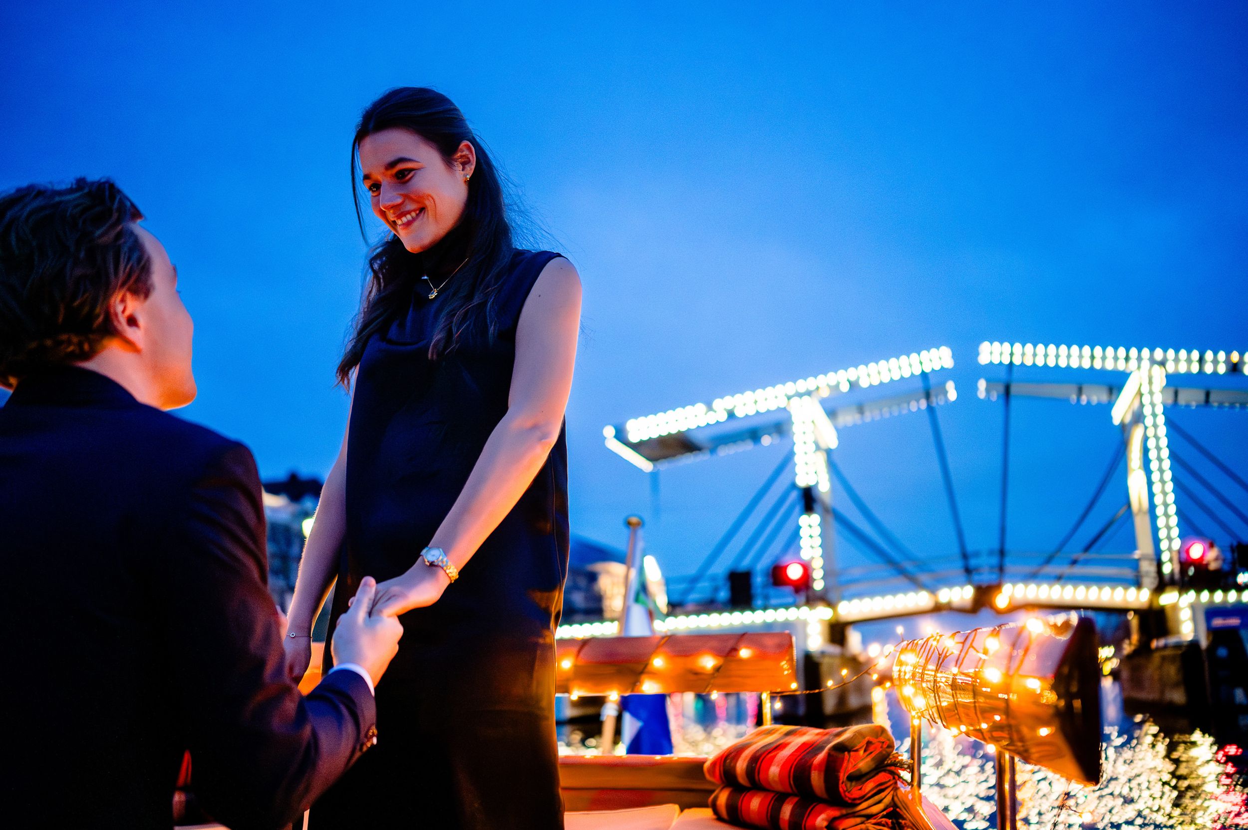 A romantic evening proposal scene set against a blue-lit backdrop with twinkling lights.