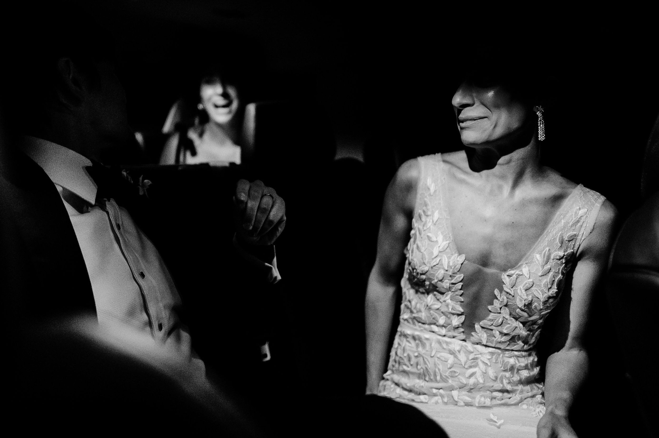 Dramatic black and white photo showing wedding dress details in low light.