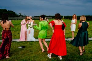 Colorfully dressed people dancing in a field under blue summer skies.