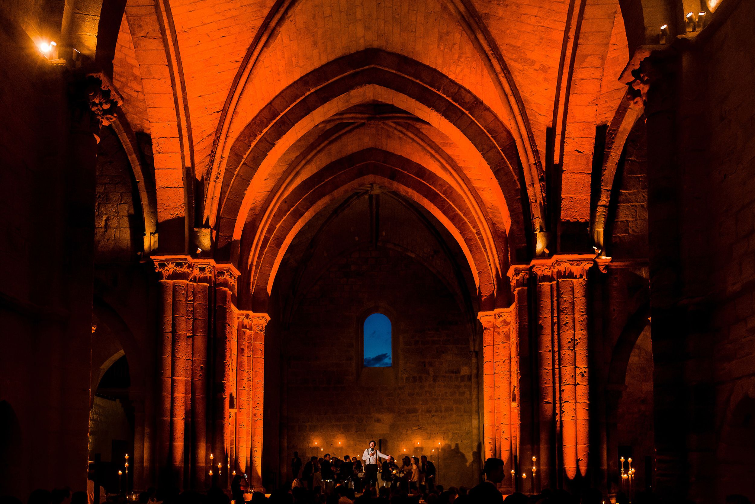 Gothic church interior illuminated in warm orange light with dramatic vaulted arches.