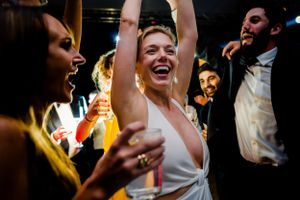 Energetic celebration with dancing and drinks at nighttime wedding reception.