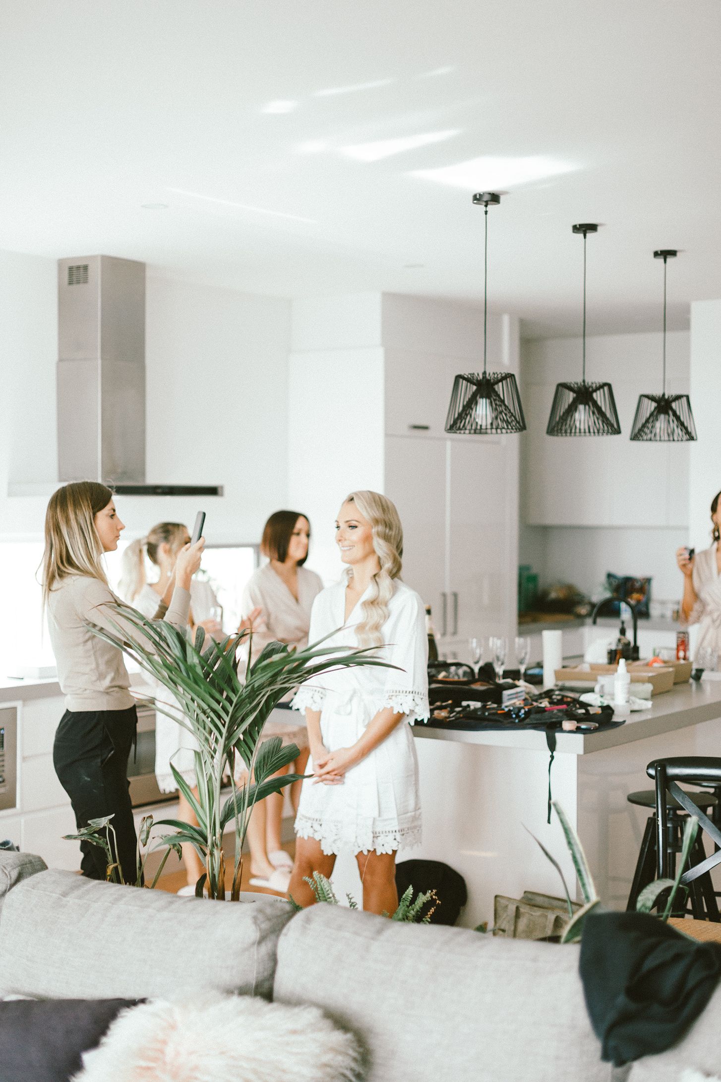 Bright modern kitchen with wedding preparation scene and decorative pendant lights.