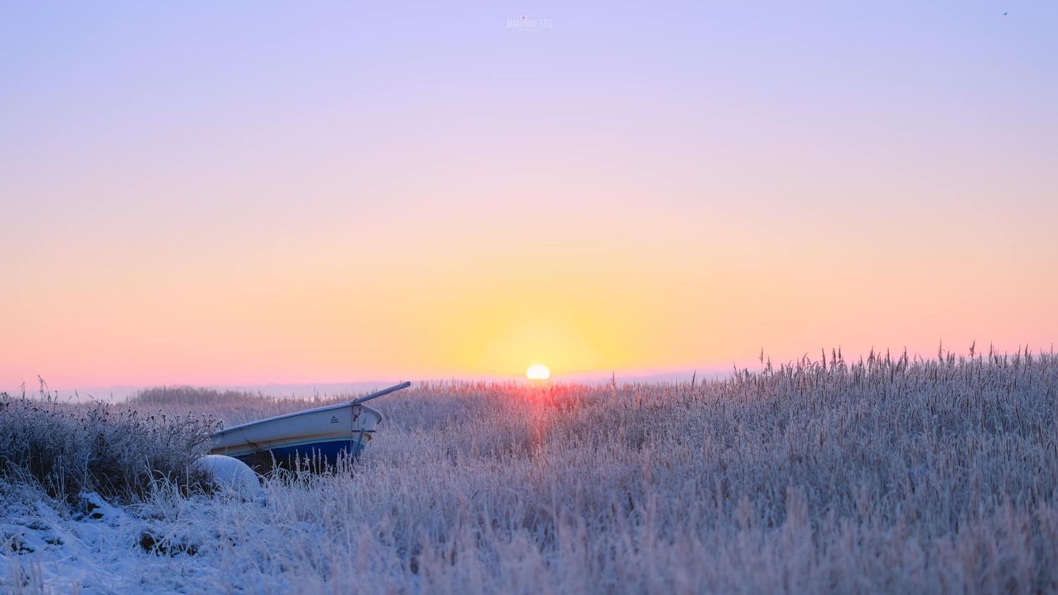 Snowy winter landscape with dramatic sunrise over frozen fields.