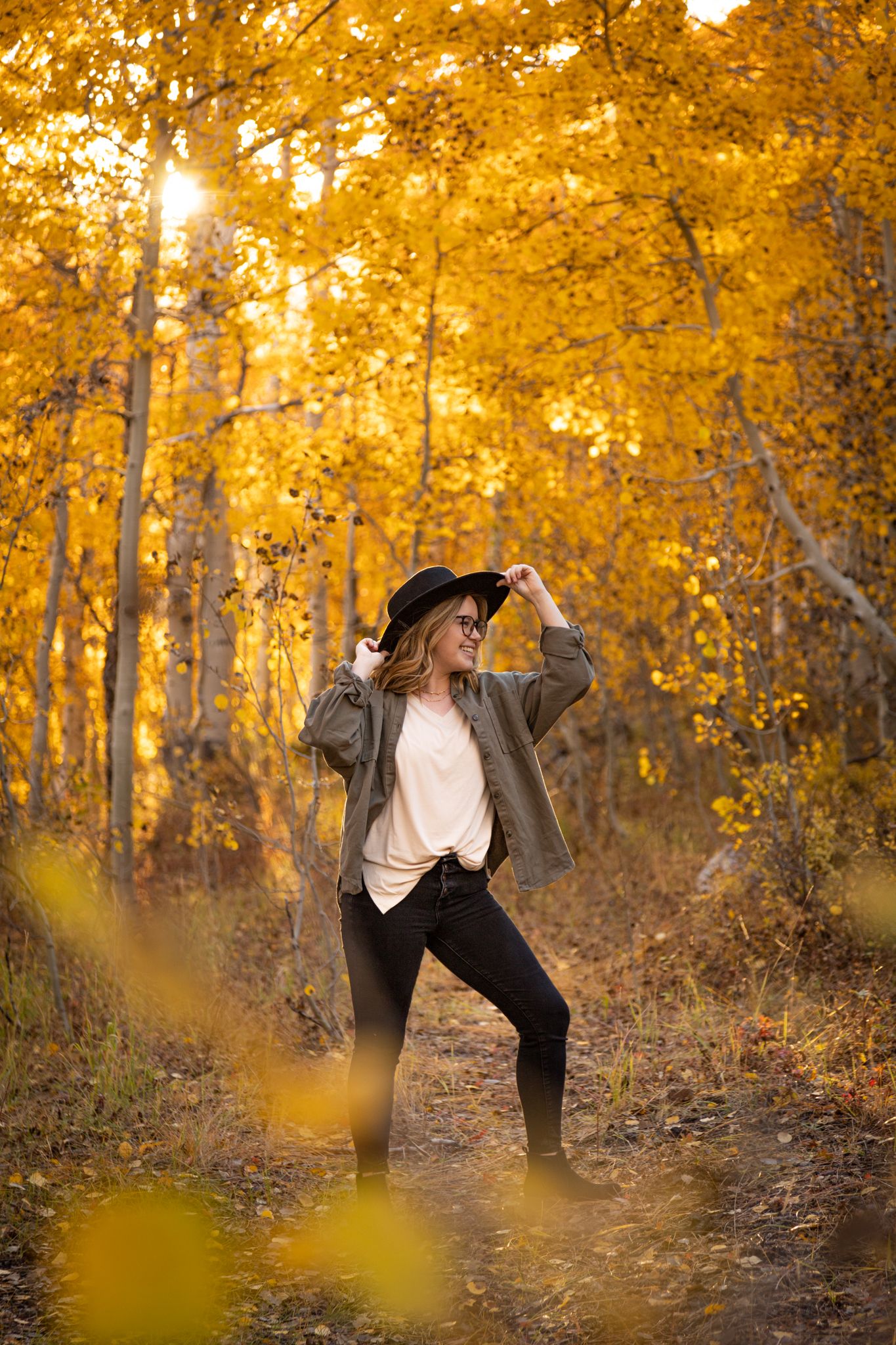 Figure dancing in a forest filled with golden autumn aspen trees and falling leaves.