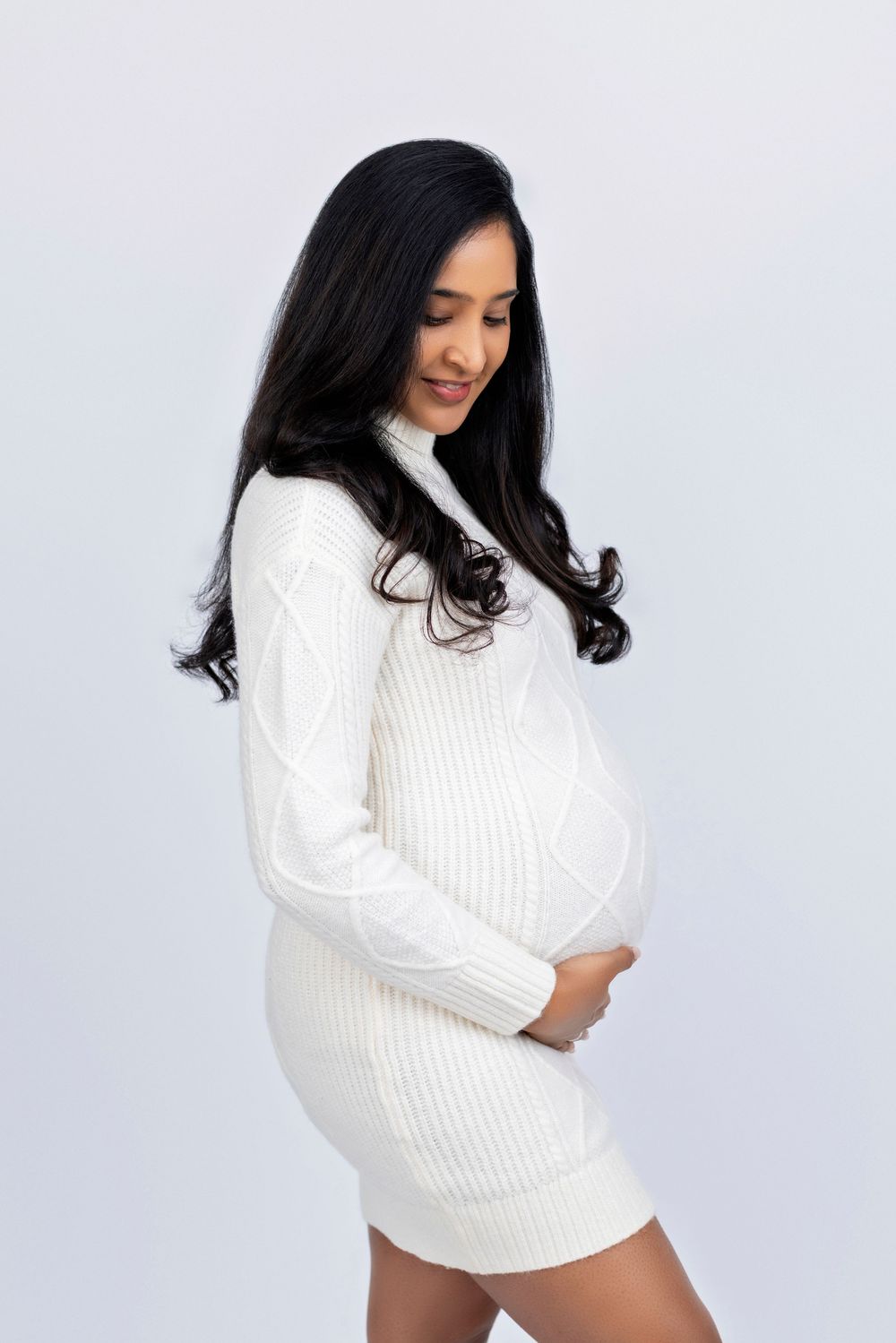 Woman in white knit sweater poses against light background in a series of intimate lifestyle portraits.