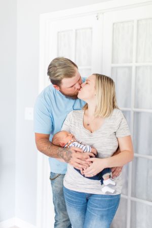 Intimate family moment while holding their newborn baby in white room during a lifestyle newborn session  in Springfield, MO.