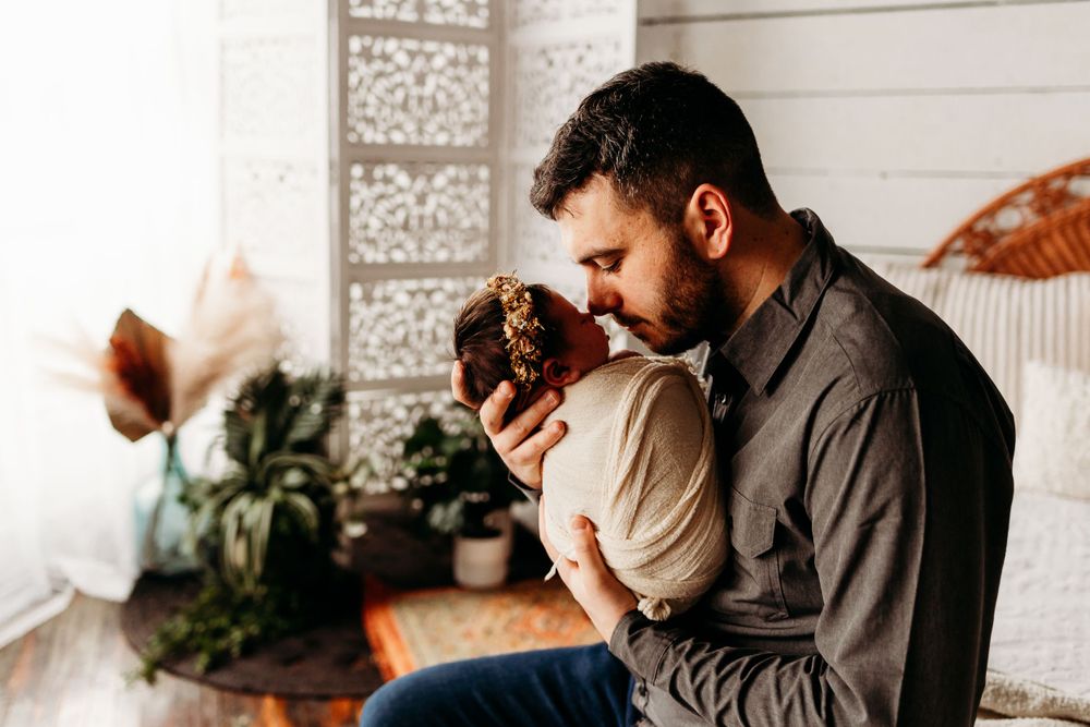 Intimate moment with swaddled newborn in warm indoor setting.