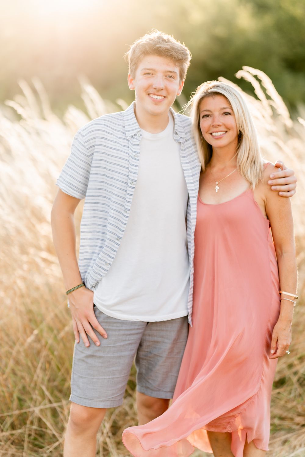 Family photos of a son and mother together in a sunlit field of tall grass, wearing casual summer outfits at sunset.