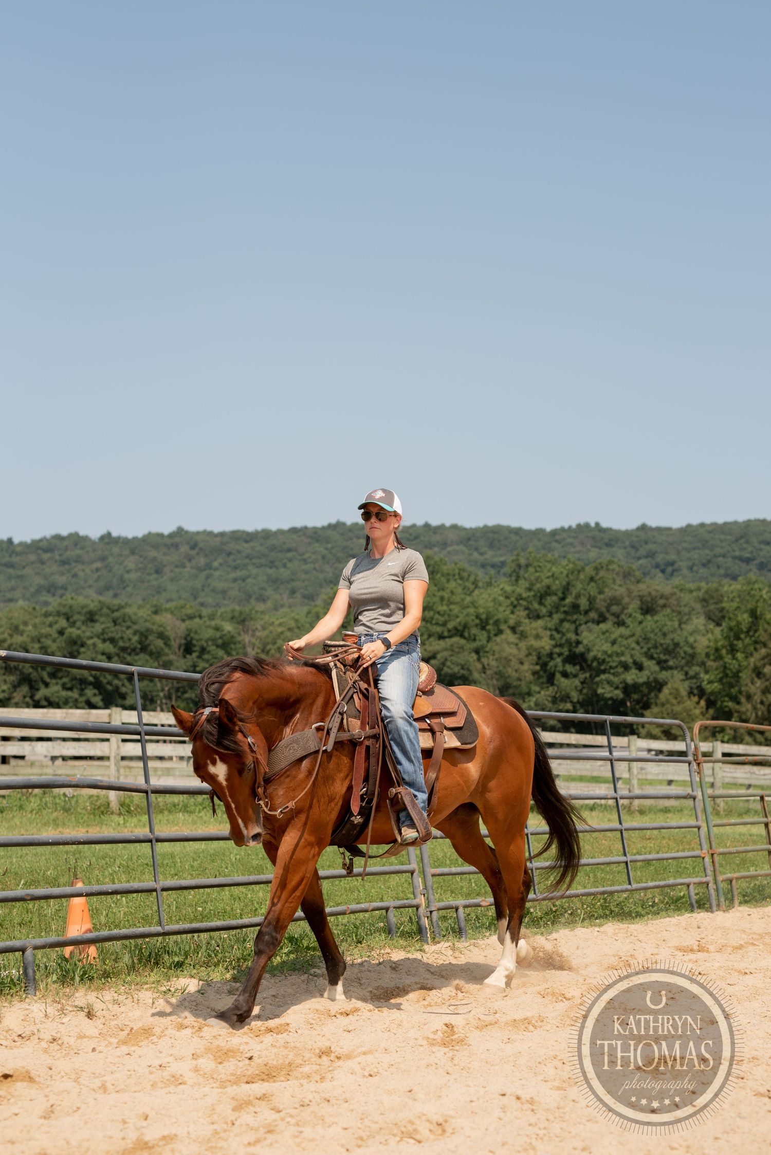 A rider practices horsemanship on a chestnut horse in a fenced arena on a sunny day.