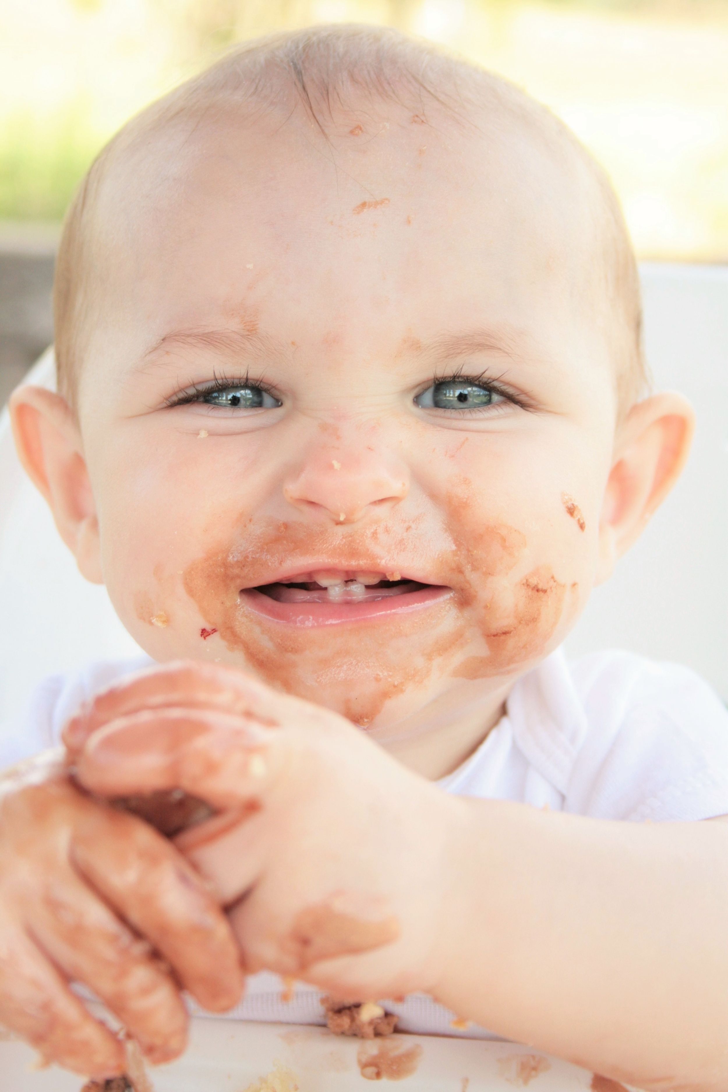 Portrait of 1 year old smash cake photo, with toddler covered in chocolate.