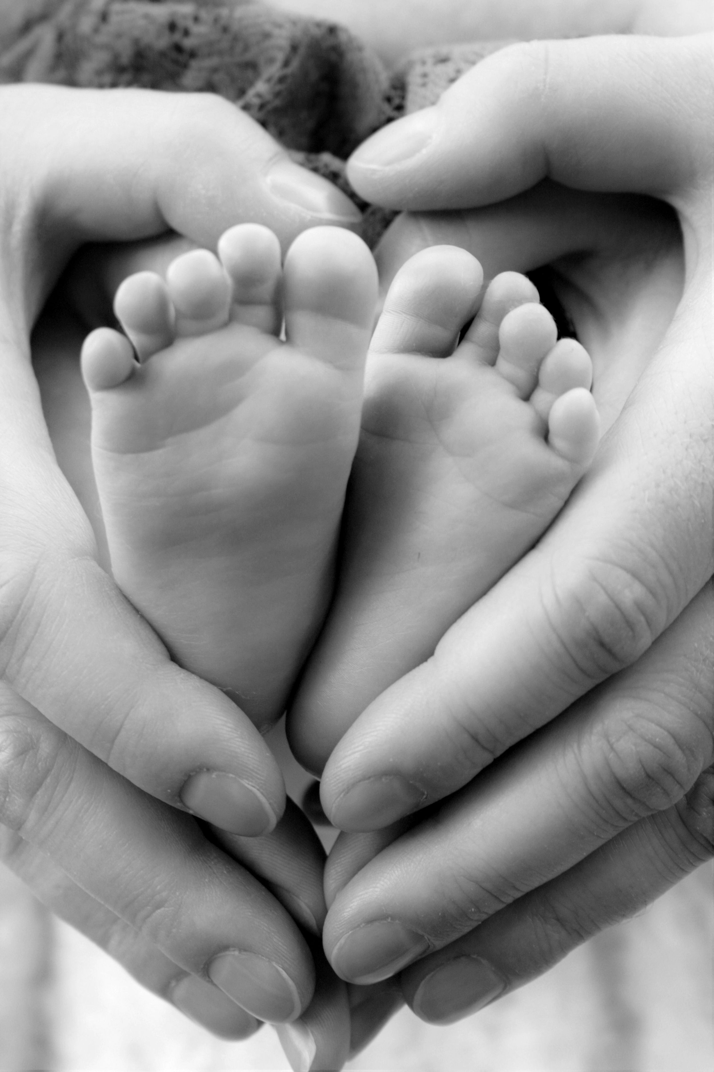 Newborn portrait of parents making a heart with their hands around newborn's tiny feet.