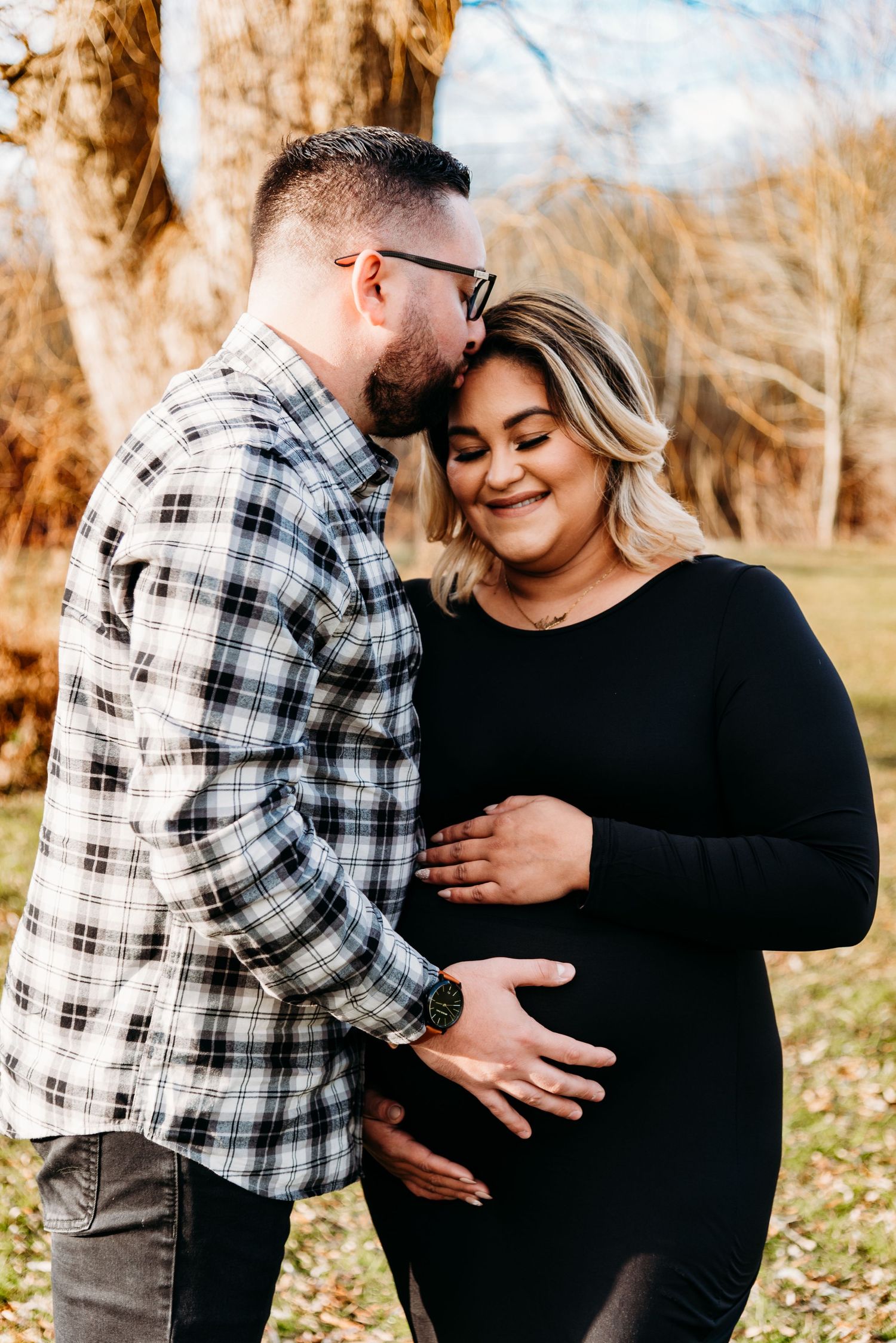 Expecting couple shares intimate moment outdoors during autumn maternity photoshoot.