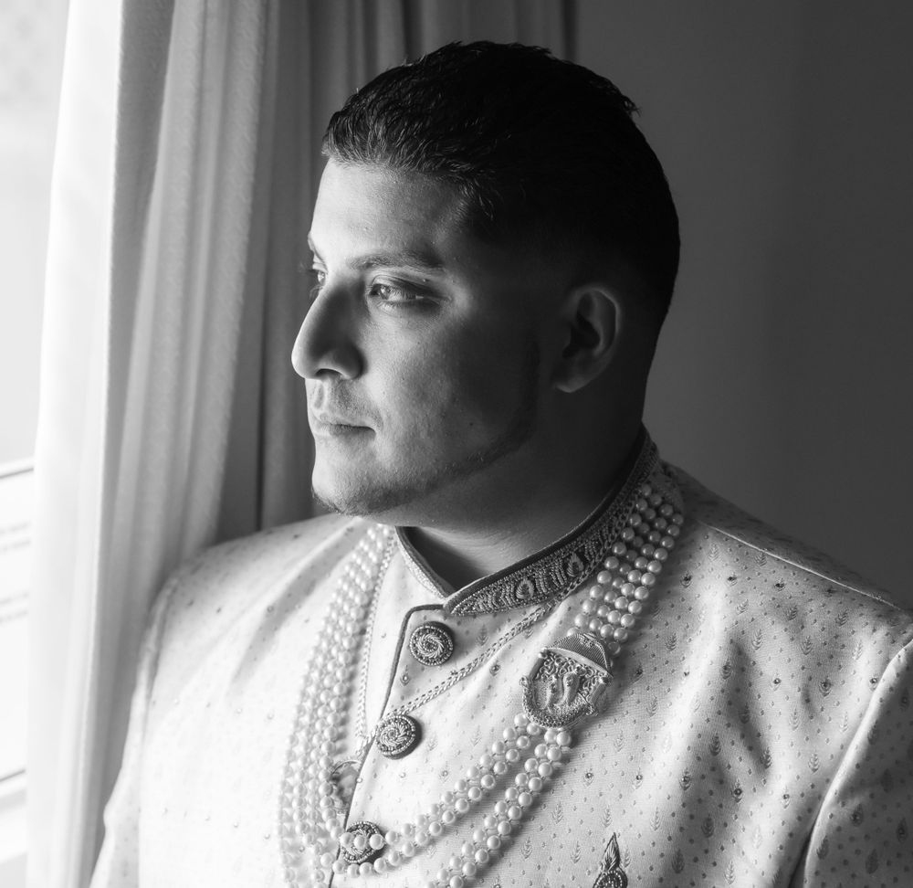 Black and white profile portrait of someone in an ornate beaded white dress looking pensively to the side.