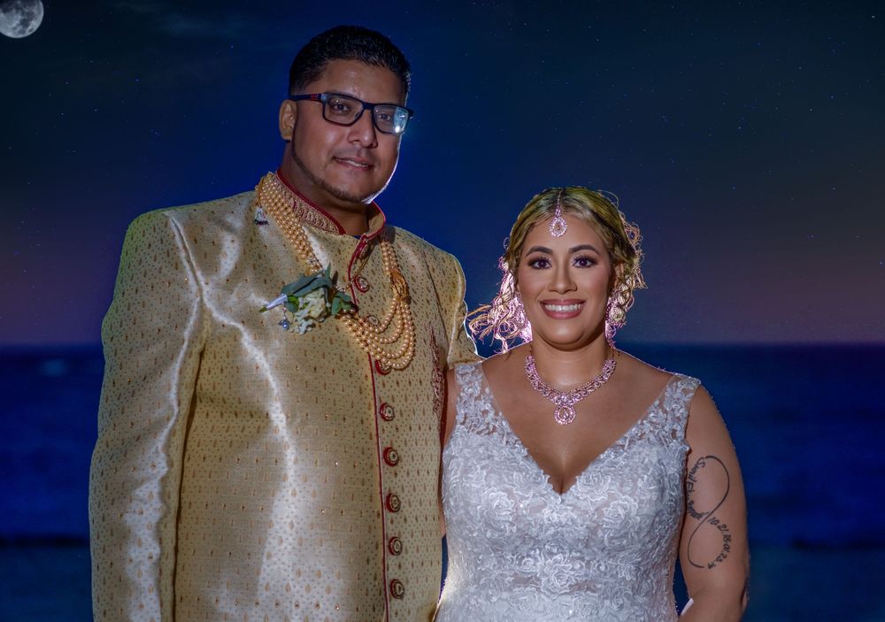 Couple in wedding attire poses together at twilight with blue lighting creating a romantic atmosphere.