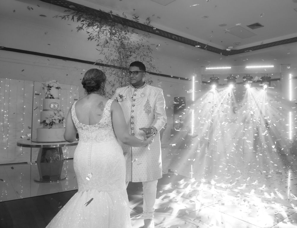 A couple stands at their wedding ceremony with dramatic lighting effects and sparklers illuminating the indoor venue.