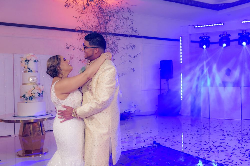 A romantic first dance at a wedding reception with purple and blue lighting illuminating the dance floor.