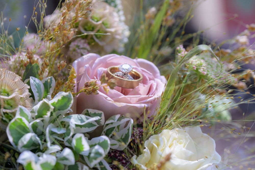 A collection of delicate pink roses and wildflowers arranged with greenery in a romantic garden-inspired design.