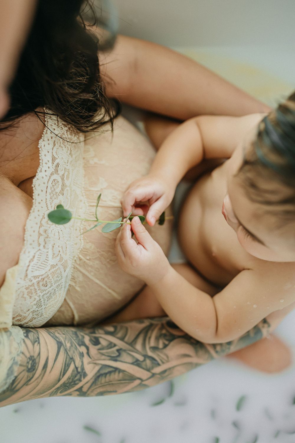 Artistic milk bath photography featuring lace details and floating eucalyptus leaves.