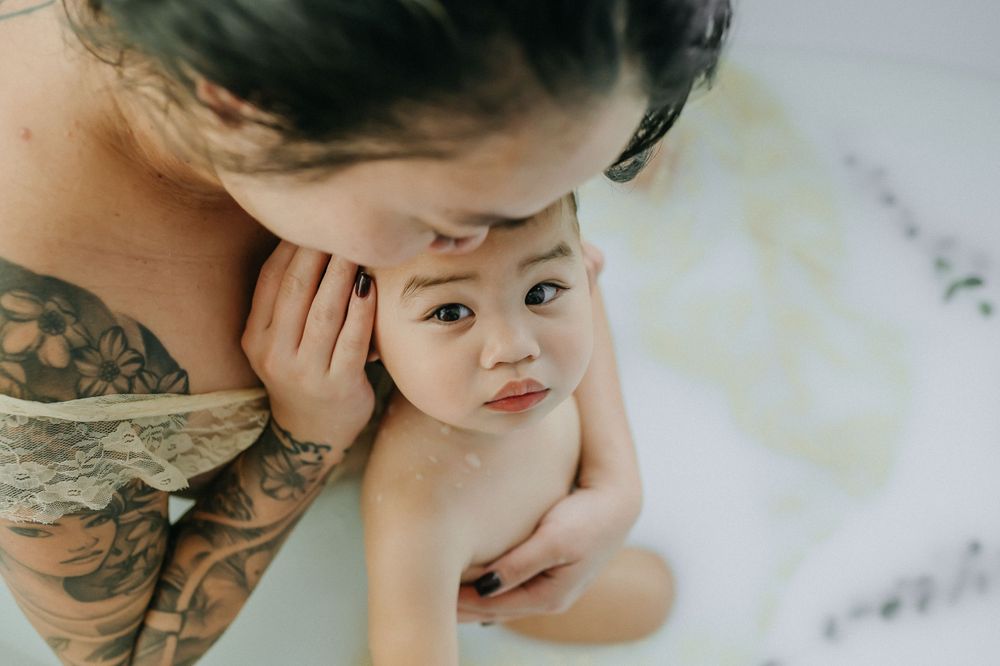 Intimate bath photo of parent and child with gentle skin-to-skin contact.