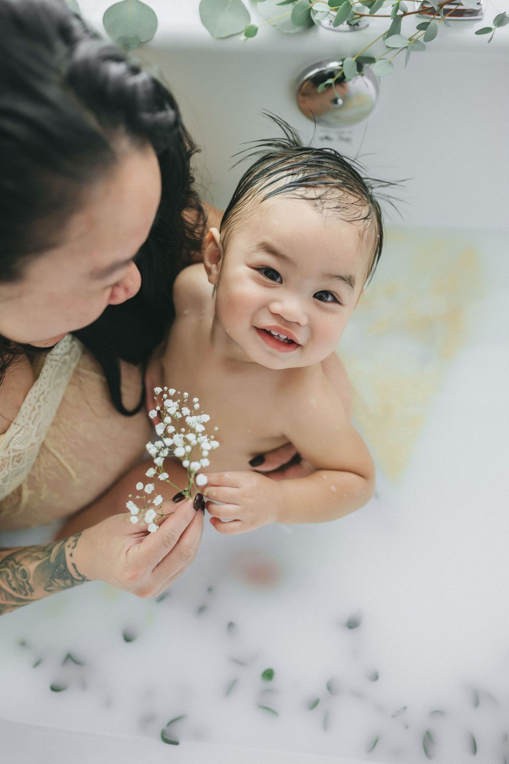 Joyful milk bath moment with baby's breath flowers and floating eucalyptus leaves.