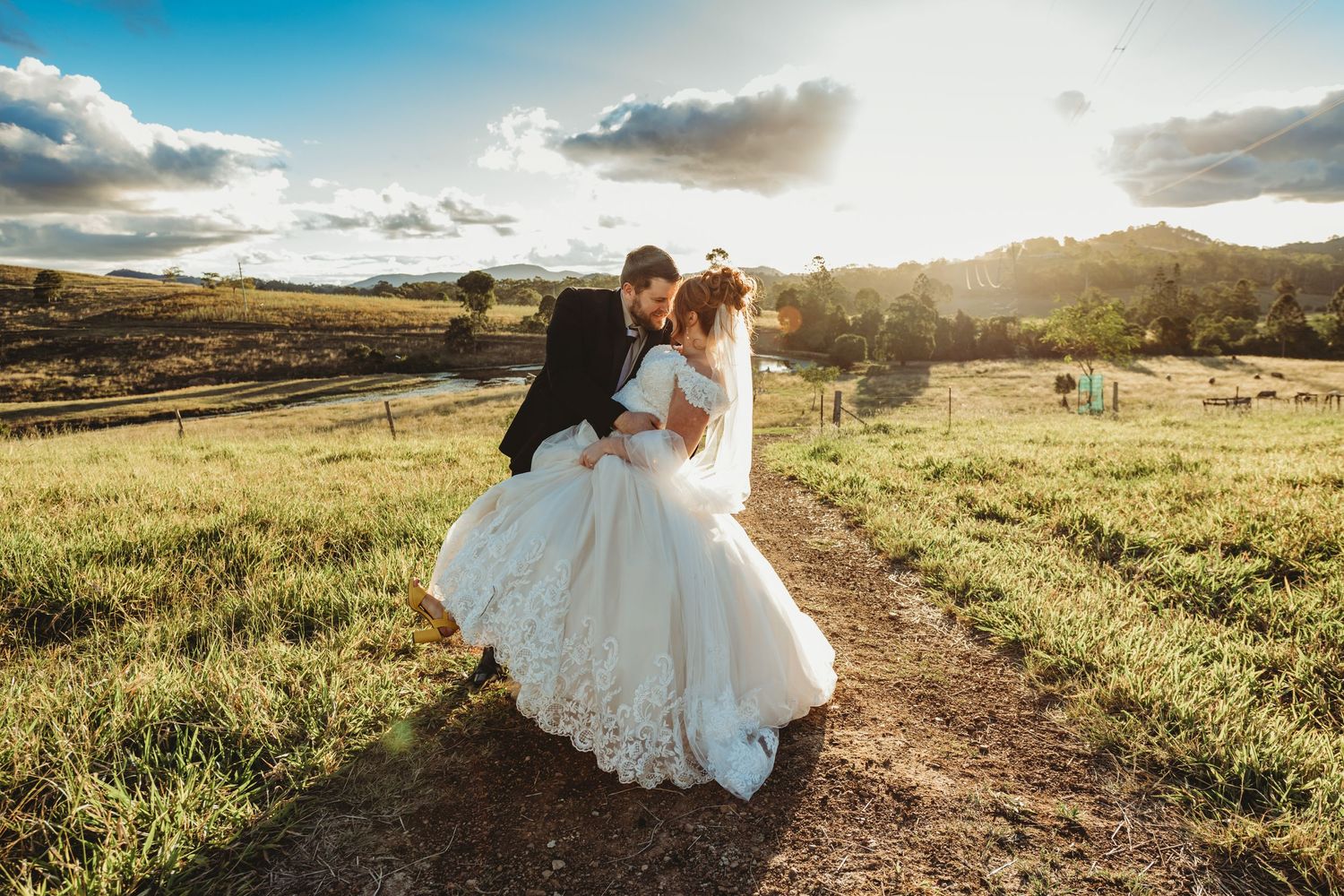 Newlyweds walking together on a hilltop path during golden hour.