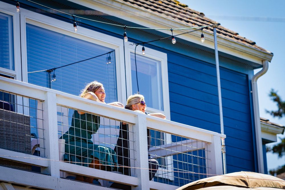 Modern coastal home exterior with white trim and blue siding features multiple levels of decks and balconies.