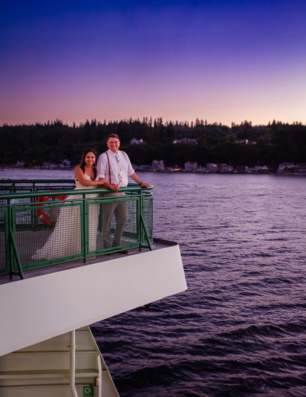 Couple enjoying a romantic sunset moment on a boat overlooking the ocean with purple twilight skies.