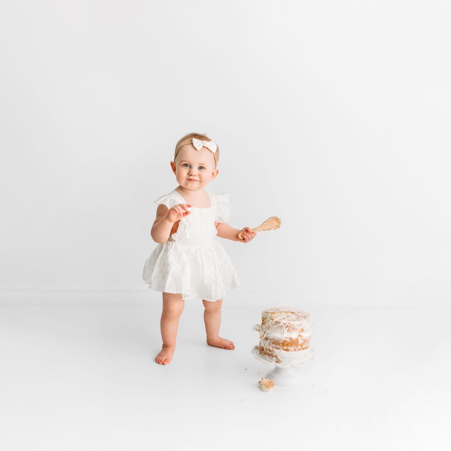 1 year old girl standing beside birthday cake