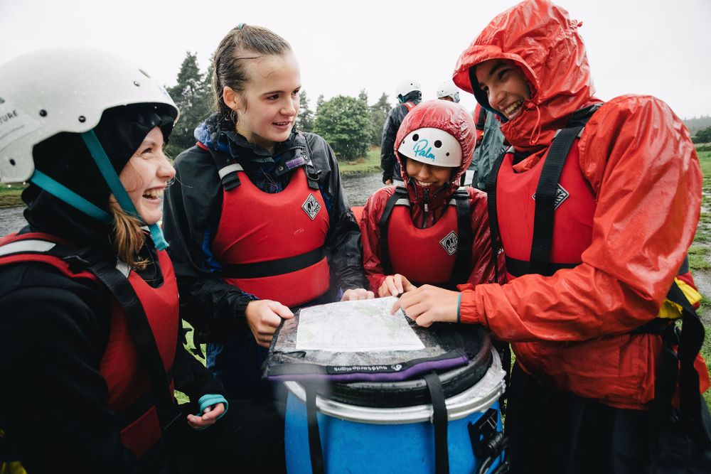 My Adventure canoe students huddle around a map on a barrel