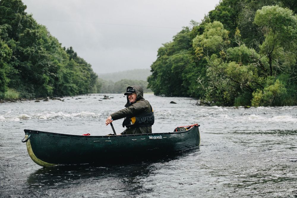 My Adventure canoe guide paddles with green trees behind