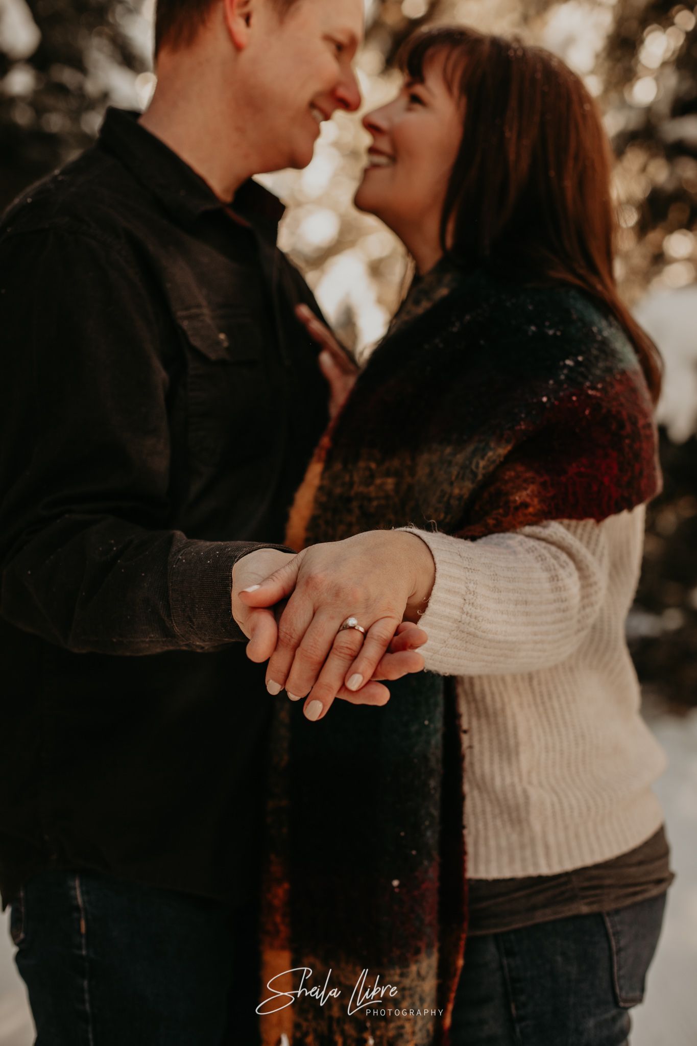 A romantic engagement photo showing a couple holding hands in winter clothing.