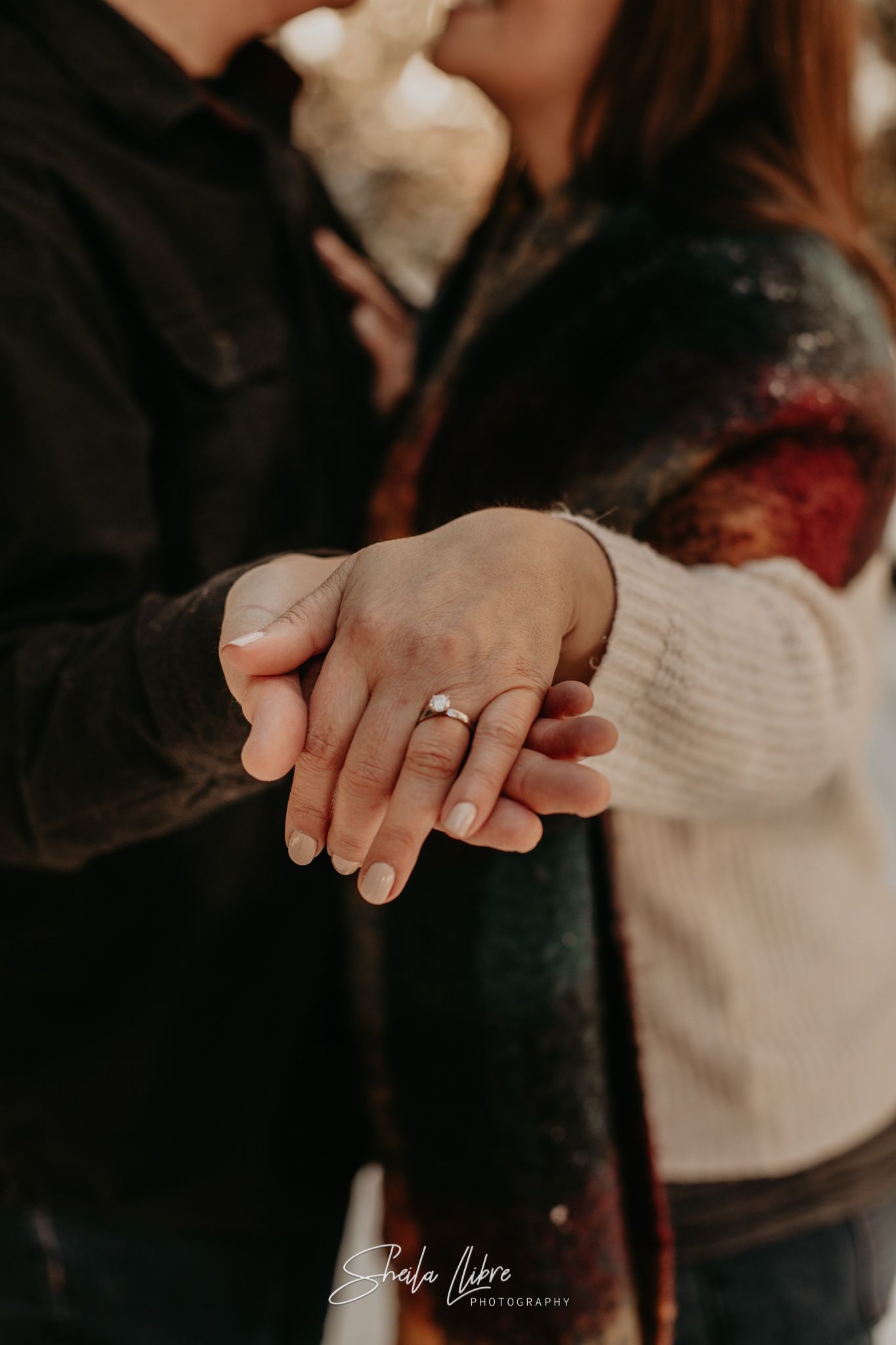 Close-up of clasped hands with an engagement ring in warm lighting during a proposal photoshoot.