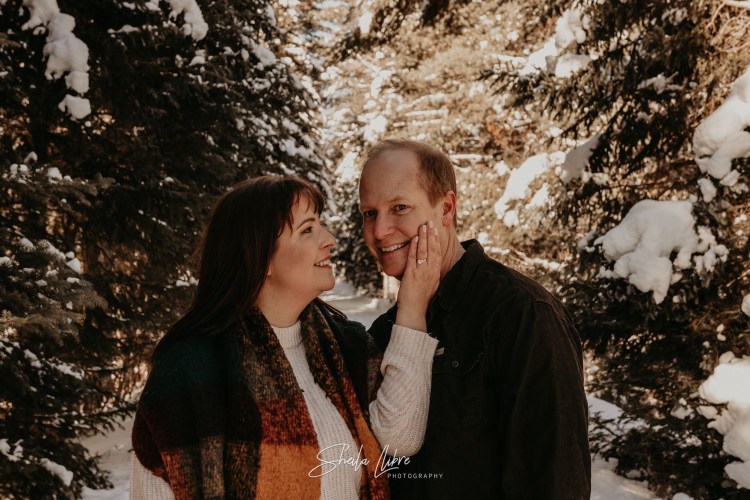 Couple sharing intimate moment in snowy winter forest setting.