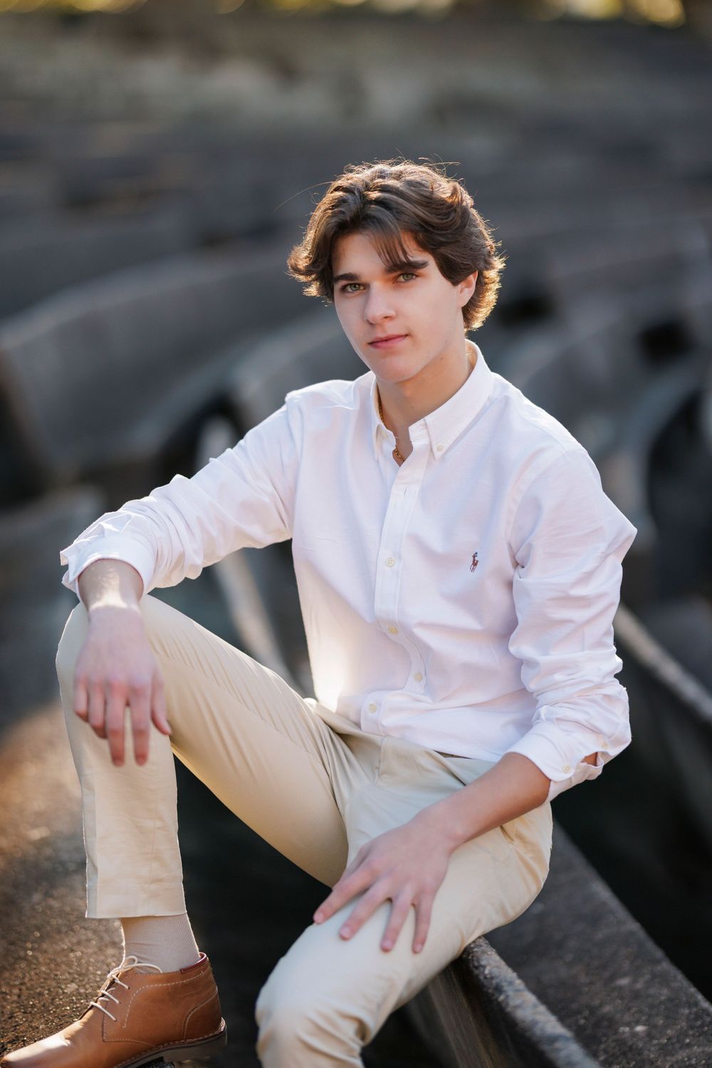Casual portrait of person in white shirt and khakis sitting on rocky terrain.