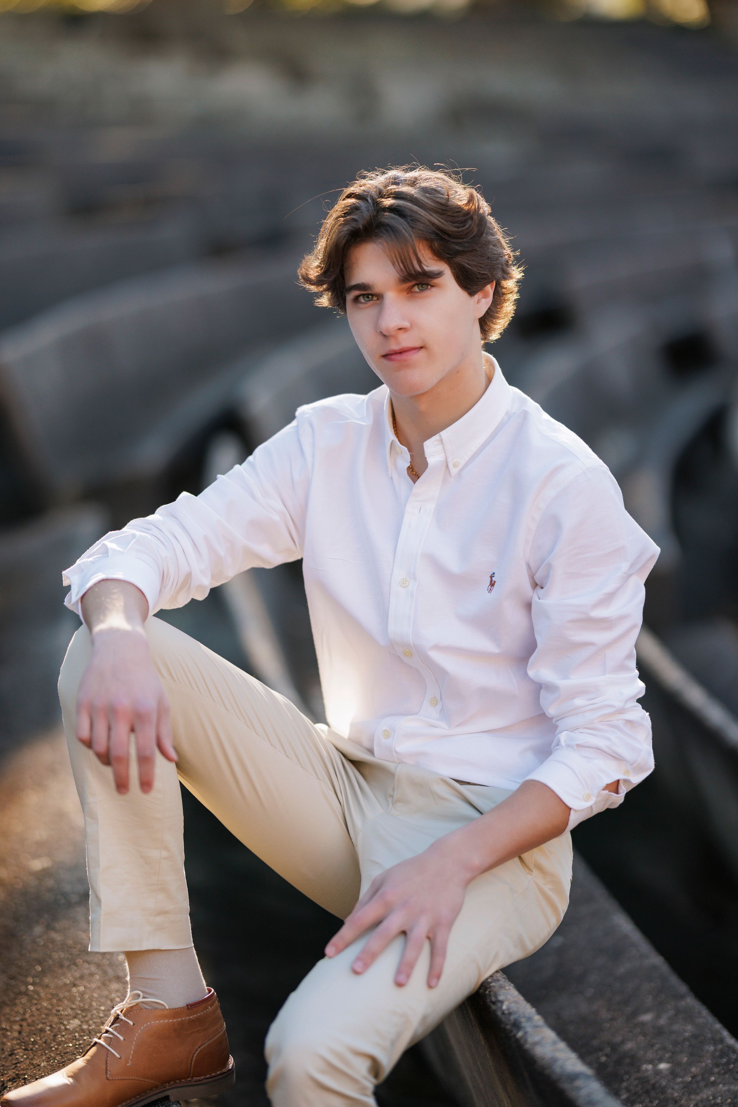 Casual portrait of person in white shirt and khakis sitting on rocky terrain.