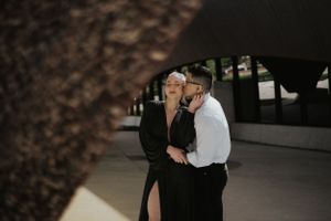 Intimate moment captured between couple in formal wear under modern architecture.