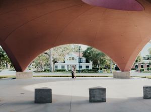 Modern curved orange architectural structure with people visible through the archway.