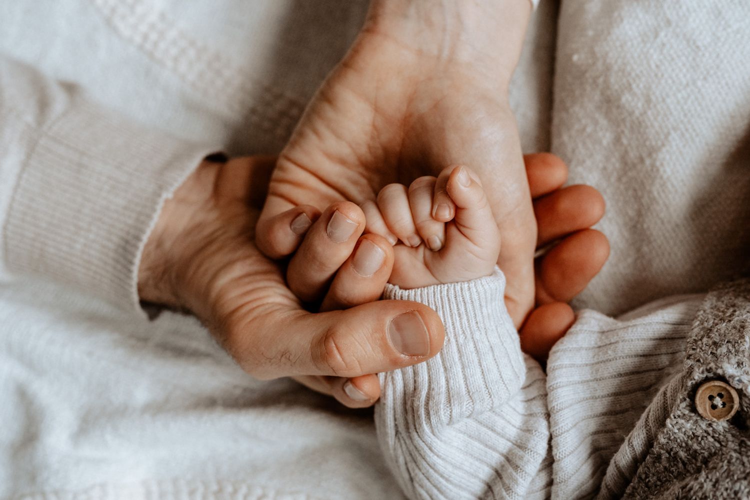 Close-up of hands holding a tiny baby sock in gentle natural lighting.