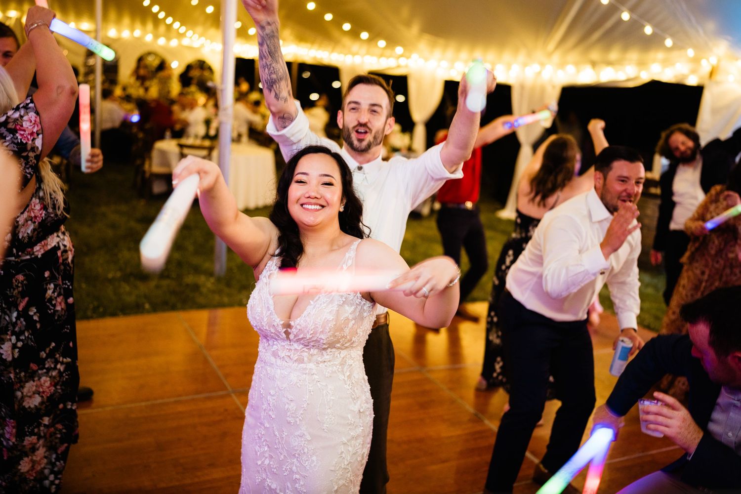 Joyful celebration with dancing guests at a tented wedding reception.
