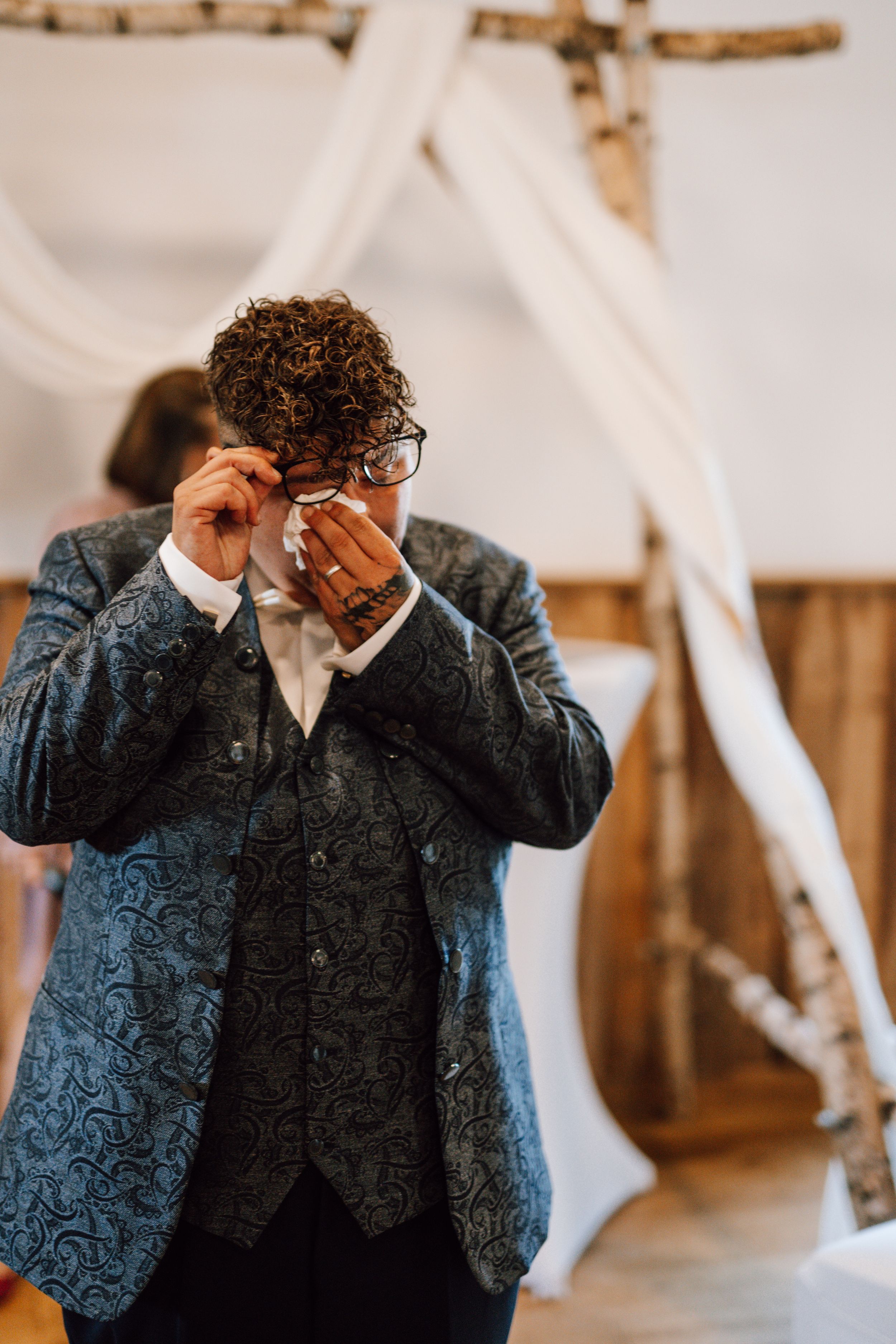 Guest wiping tears during emotional wedding ceremony.
