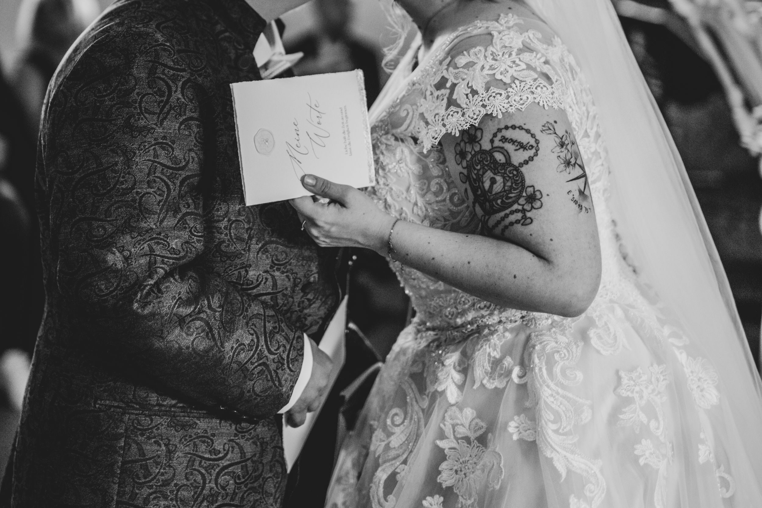 Black and white photo of couple exchanging vows during wedding ceremony.