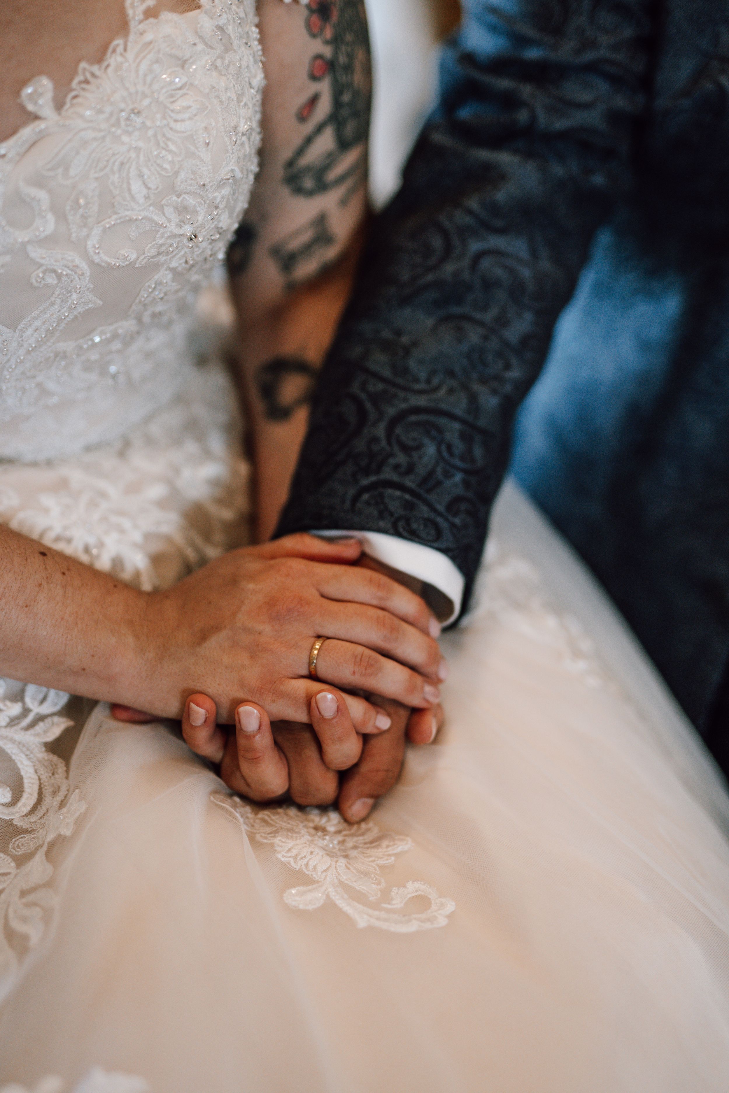 Close-up of newlyweds holding hands showing wedding rings.
