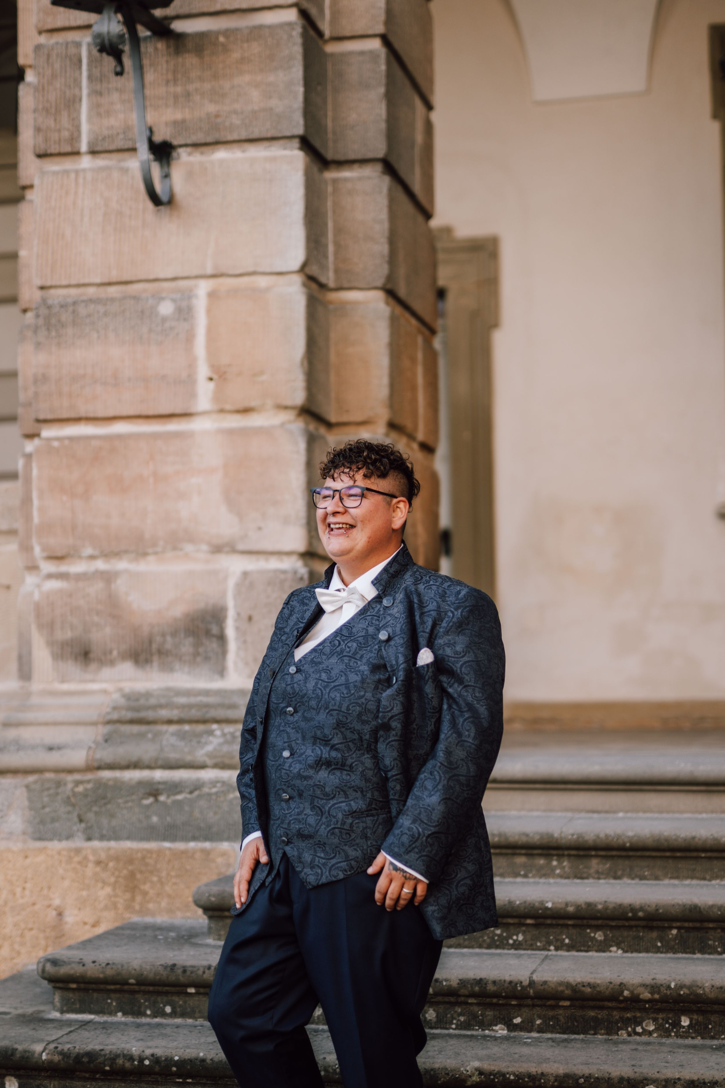 A wedding portrait on historic stone steps with classical architecture in the background.