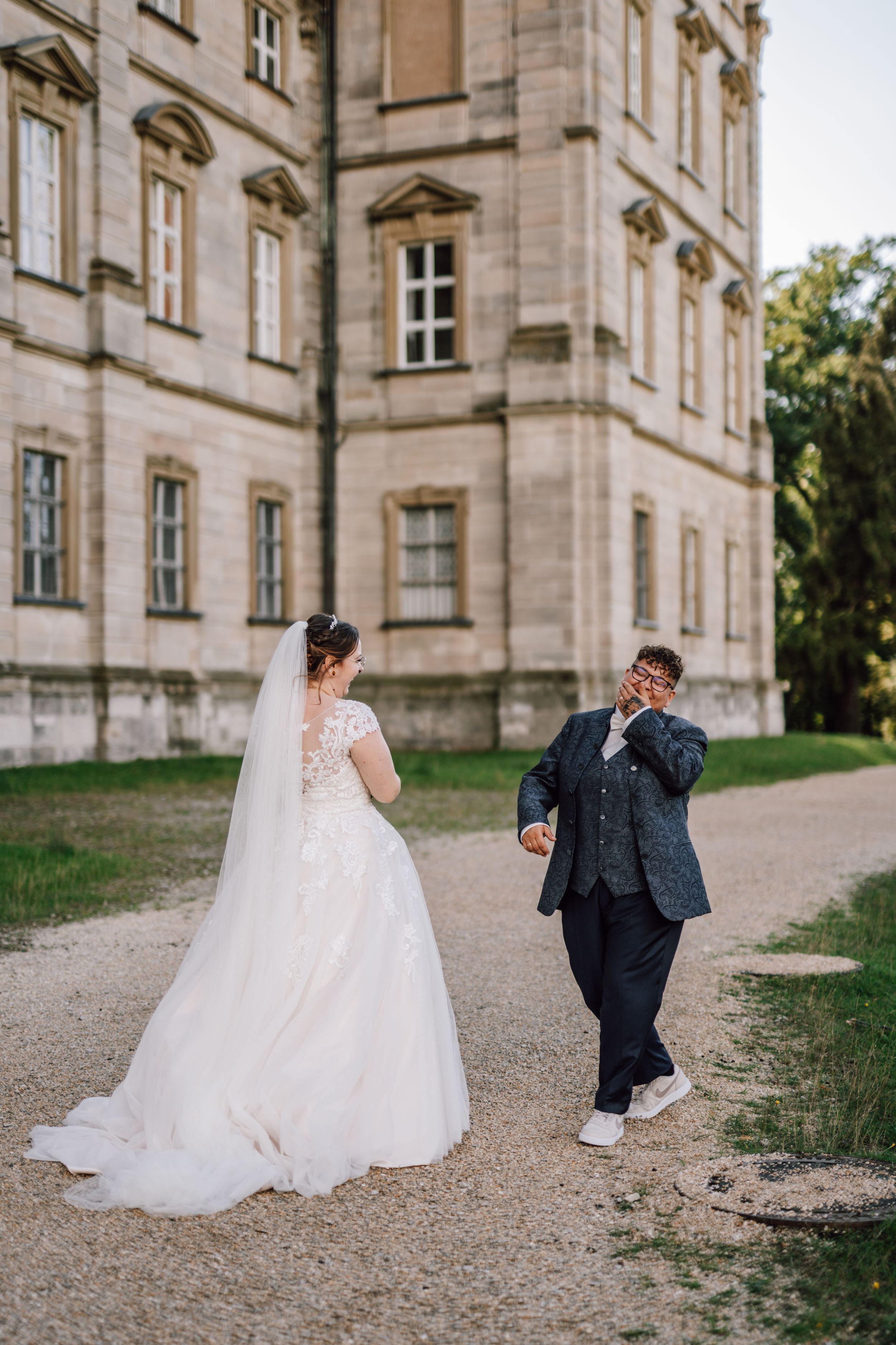 A candid wedding moment captured outside a grand historic building with stone architecture.