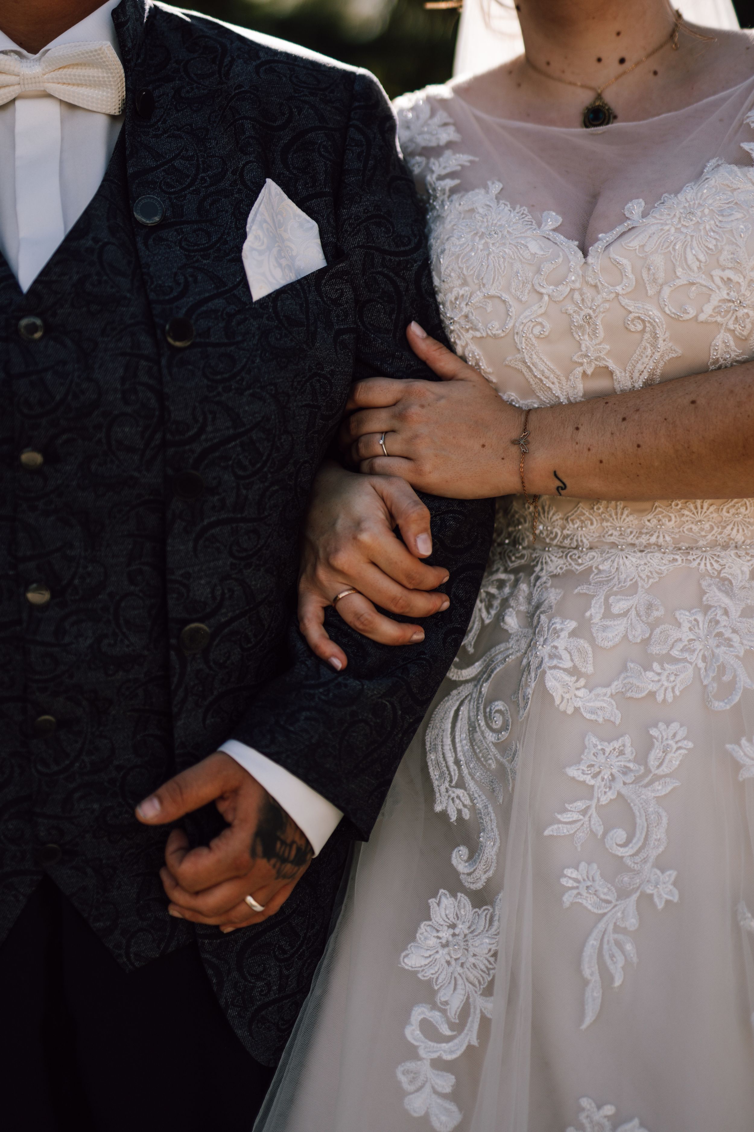 Detail shot of intricate lace wedding dress with hands tenderly placed on fabric.