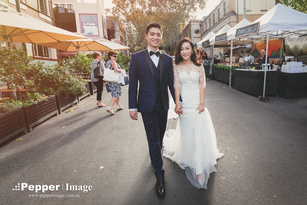 Elegant bride and groom walking through outdoor market street on their wedding day.
