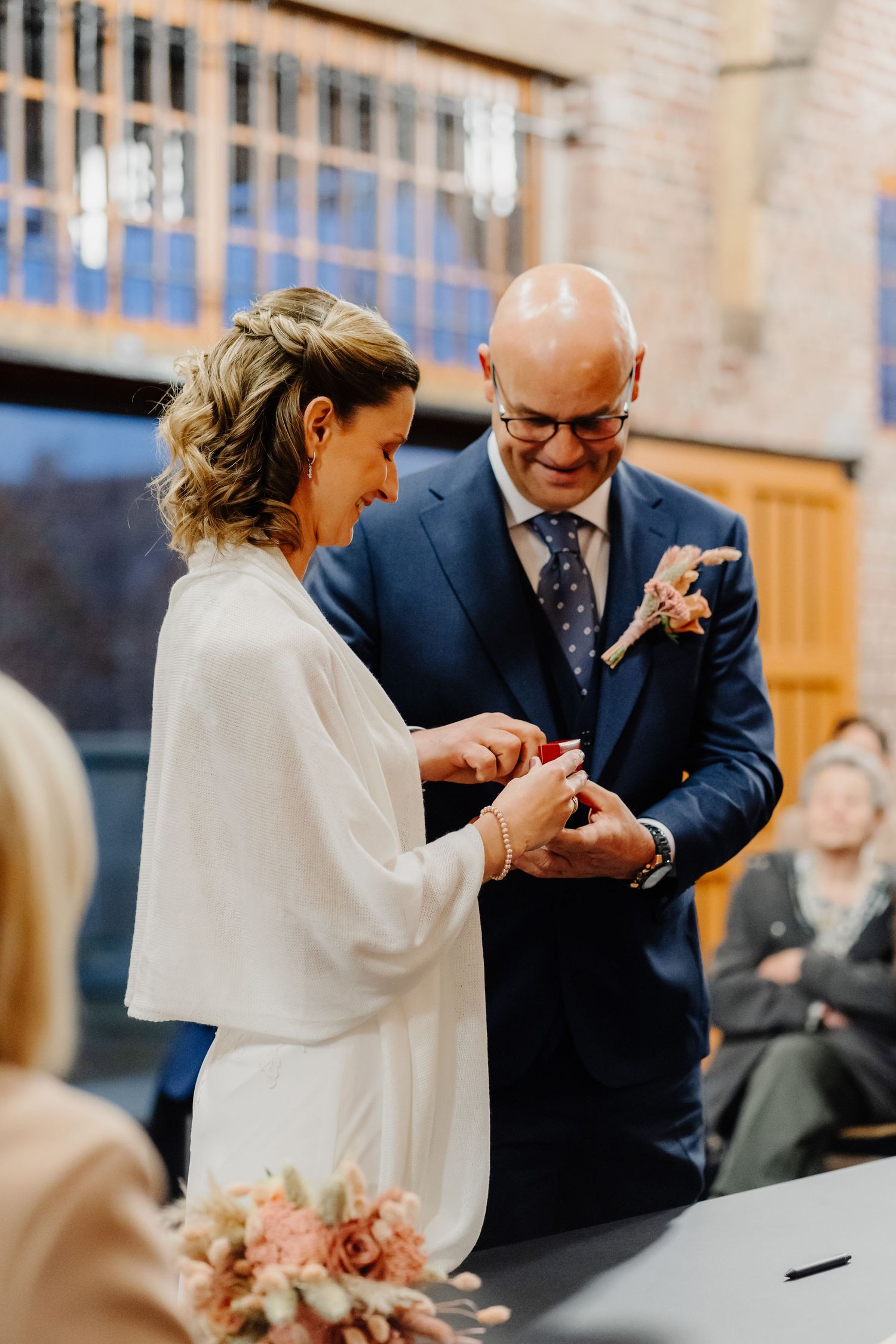 Ring exchange ceremony in an elegant indoor venue with soft lighting and floral decor.