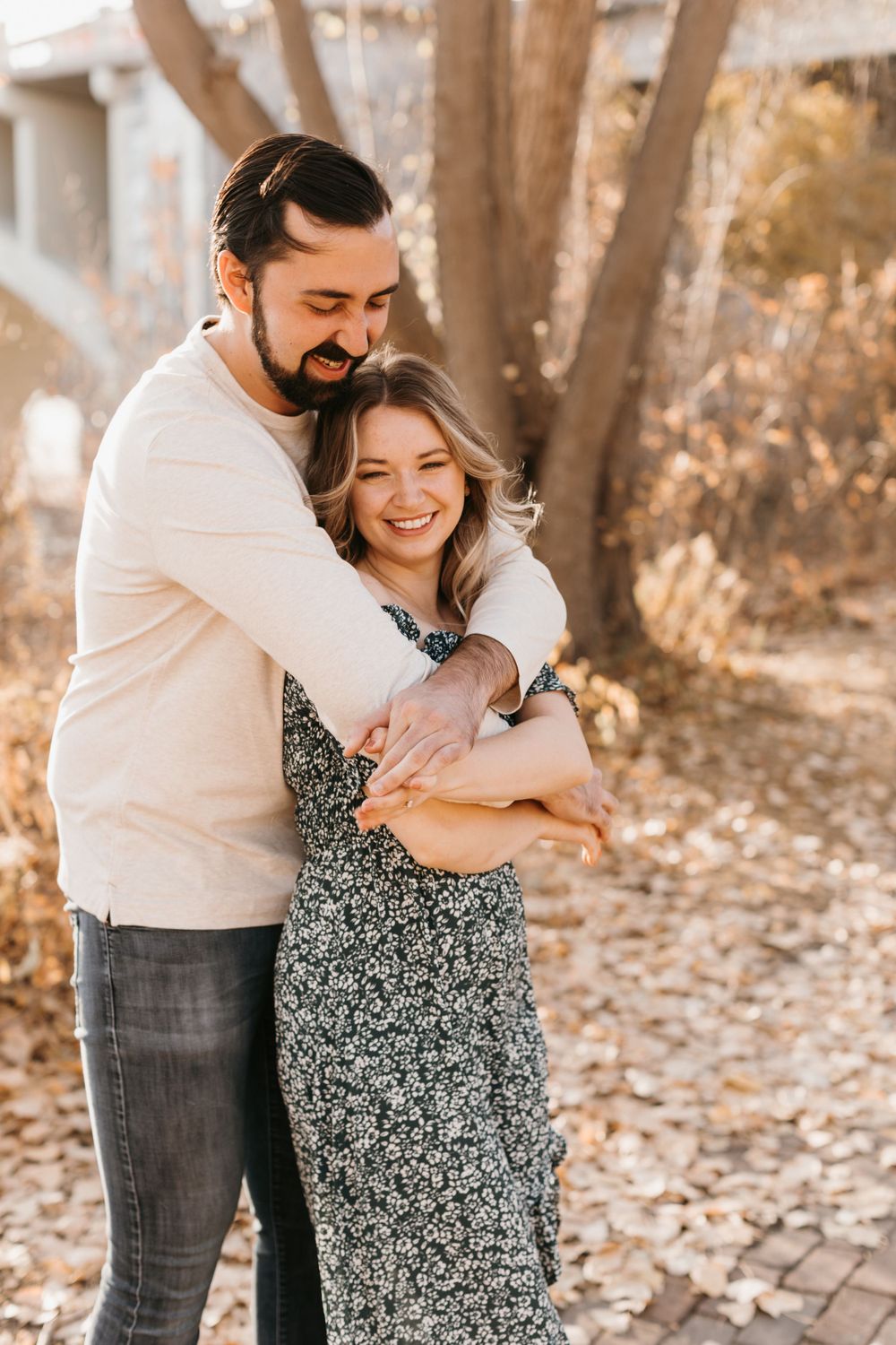 Happy couple sharing a warm embrace on a brick path surrounded by golden fall foliage.