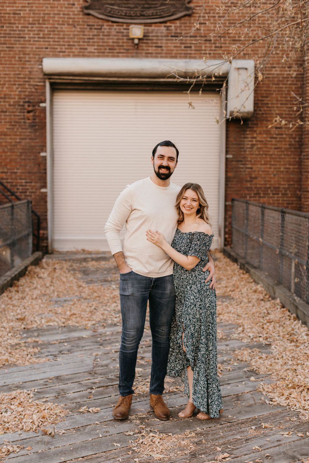 Smiling couple posing together in a charming brick alley during an engagement photo session.